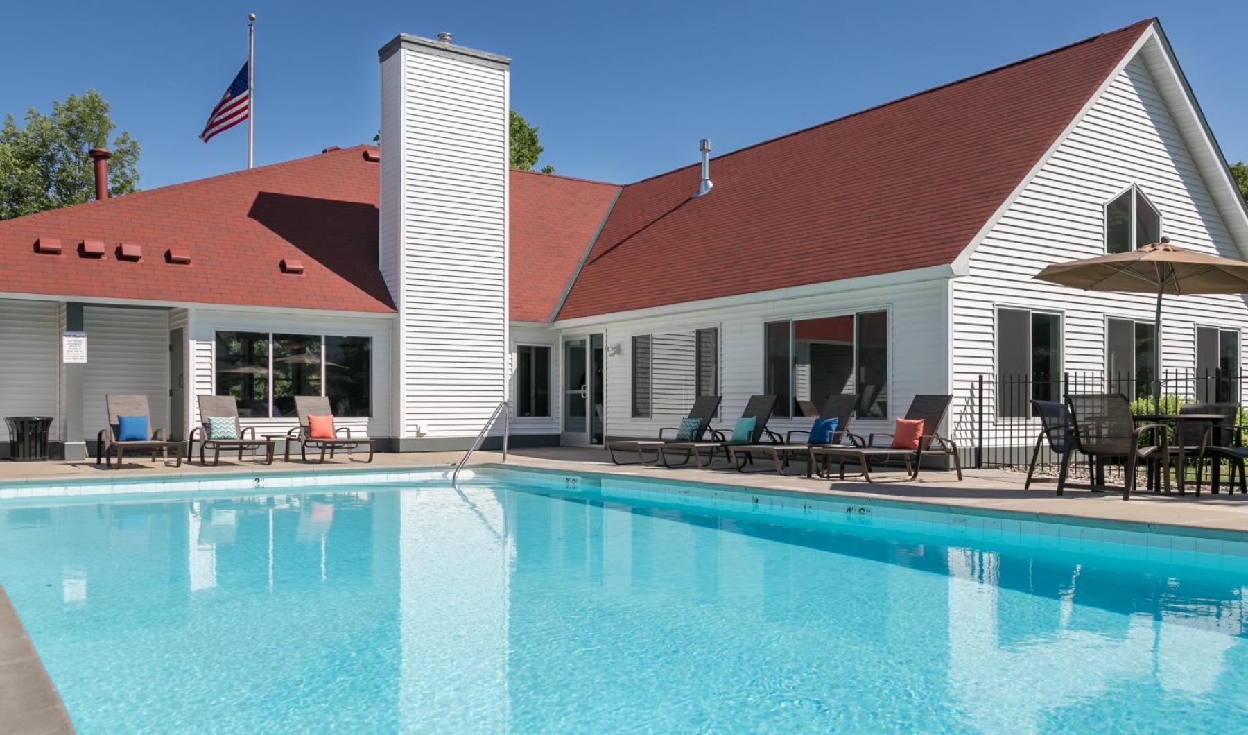 a swimming pool with chairs and a building in the background