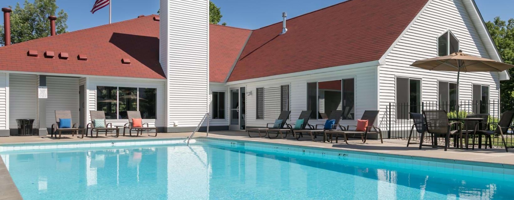 a swimming pool with chairs and a building in the background
