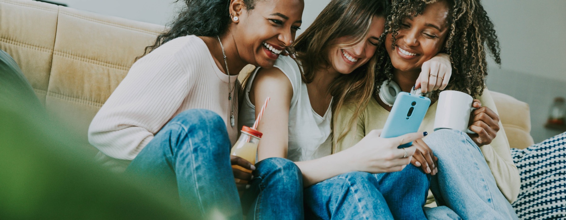 Group of women laughing on couch holding a phone
