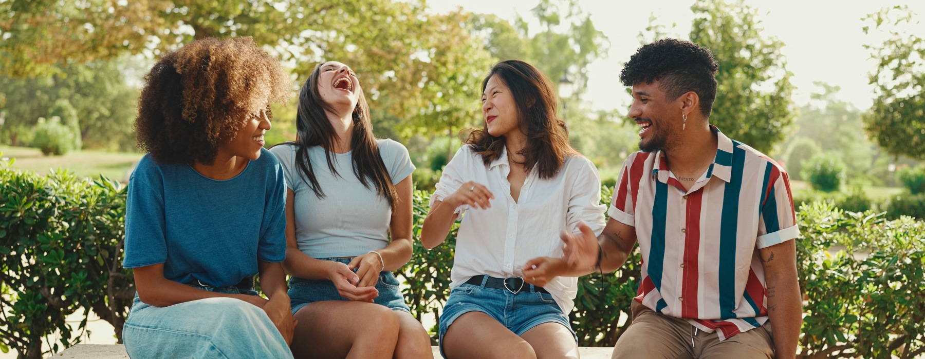 Group of friends sitting on a ledge laughing